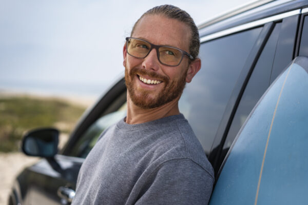 man in spectacles leaning on car